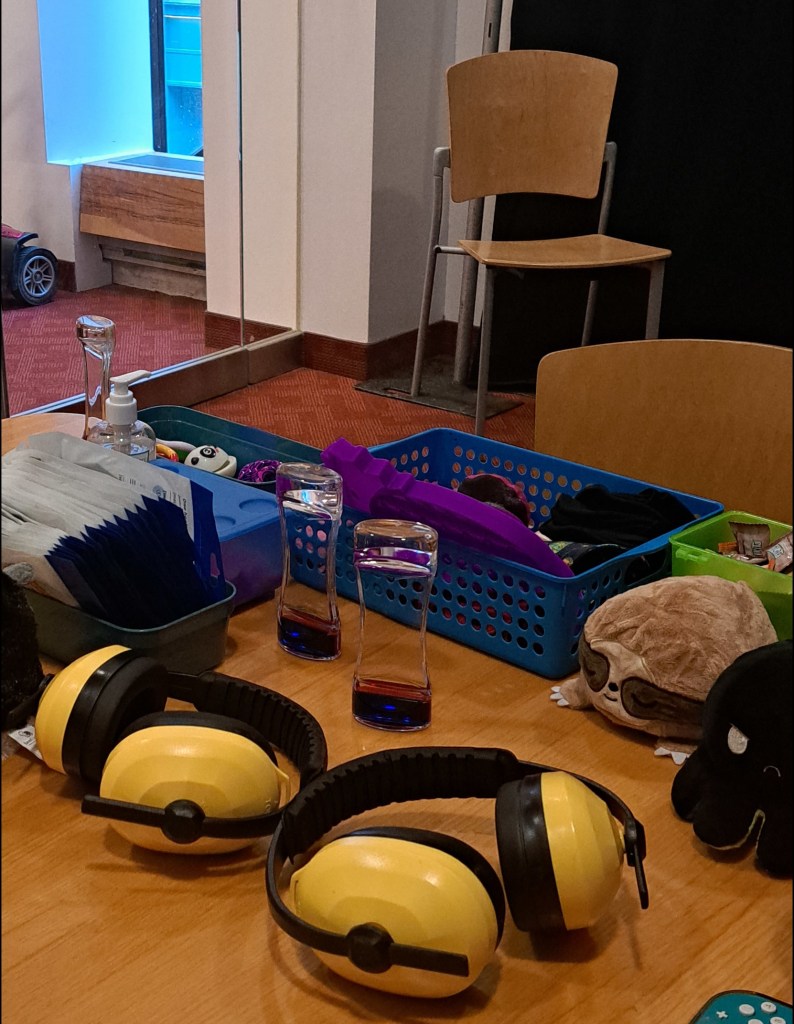 Photograph of a table wit ear defenders and a variety of fidgets and stim toys on top.