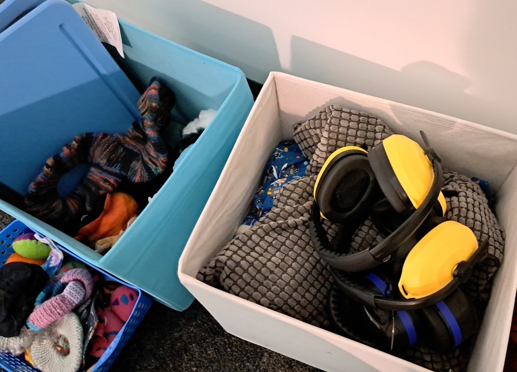 Baskets with weighted lap pads, noise blocking headphones, eye masks, and large crochet stim toys.